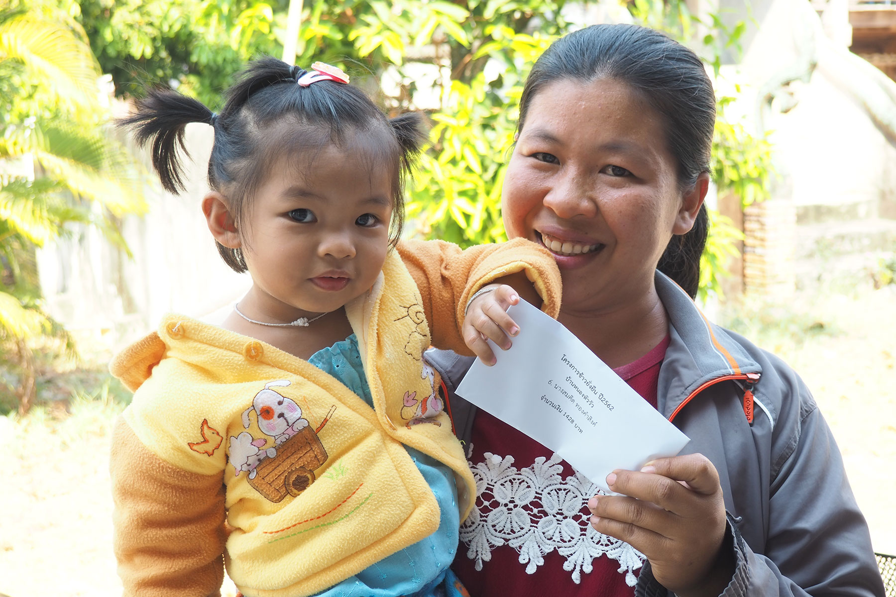 A farmer from Samrong district of Ubon Ratchathani province takes her daughter to the community hall to receive the bonus together.
